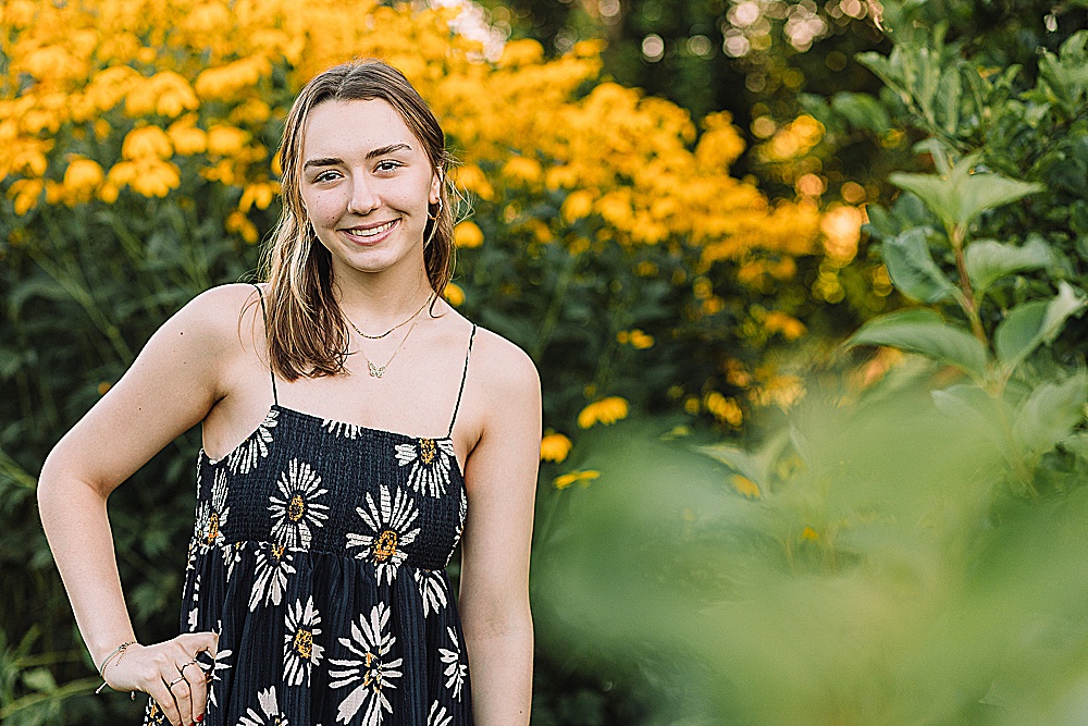 Vermont high school senior wearing a sunflower dress standing in a garden of yellow flowers
