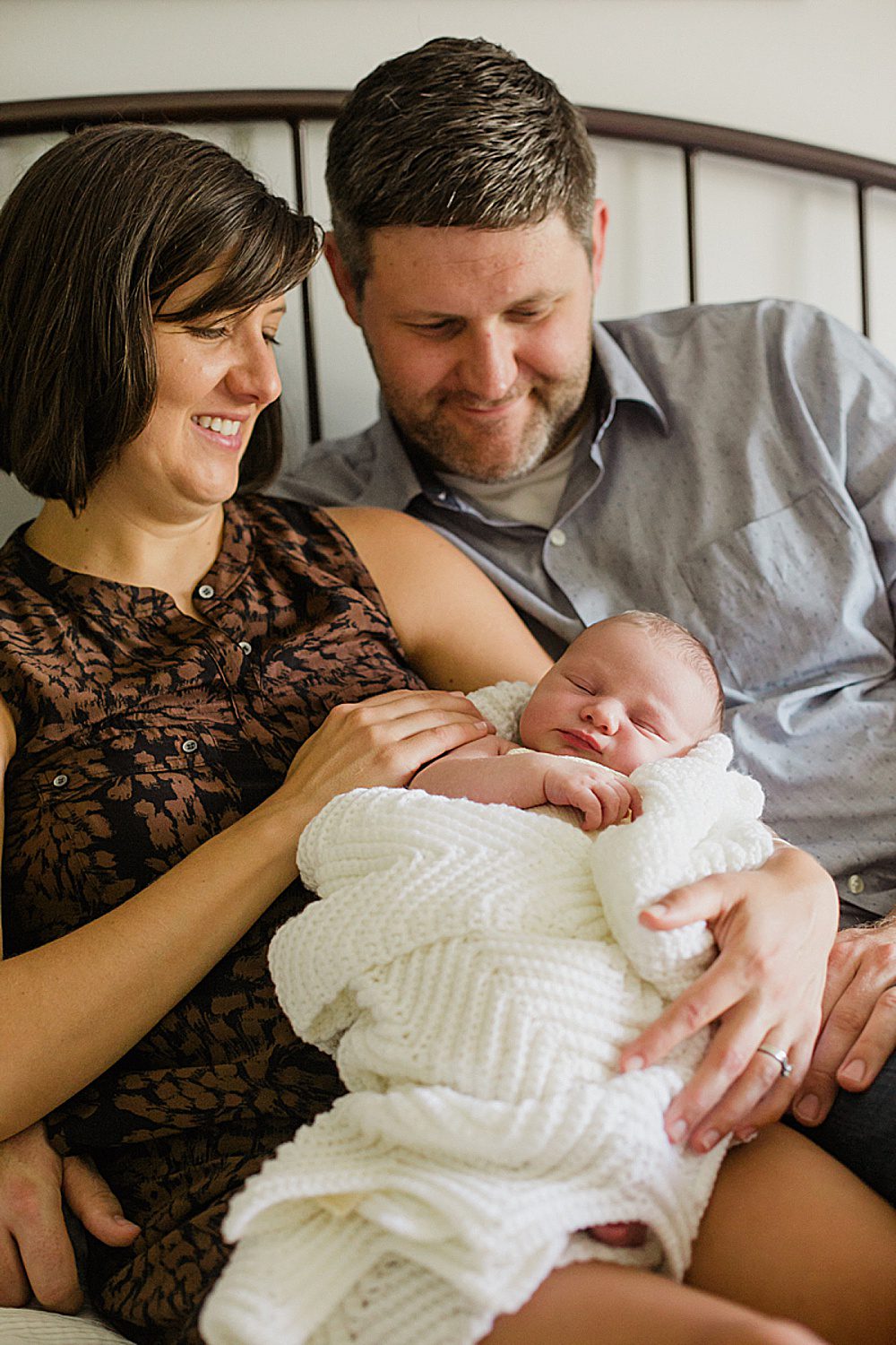 Vermont photo of mom and dad smiling at newborn daughter inside their home